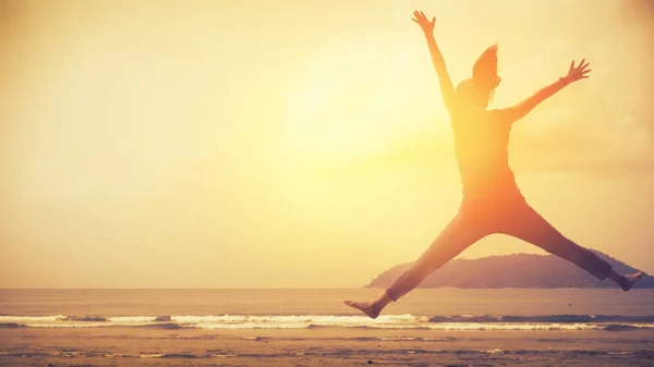 Wohlfühl- und Freiheitskonzept. Kopierraum einer glücklichen Frau, die am Strand des tropischen Sonnenuntergangs springt. — Stockfoto