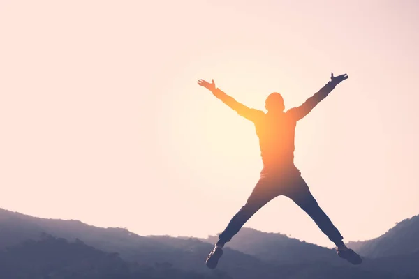 Happy man jumping at top of mountain with sunset sky abstract background. — Stock Photo, Image