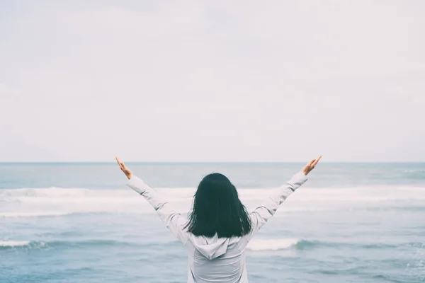 Liberdade se sentir bem e viajar conceito de aventura. Copiar espaço de silhueta mulher levantando as mãos com céu azul e nuvem branca no fundo da praia . — Fotografia de Stock