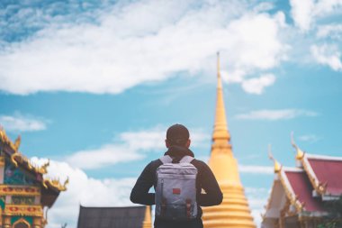 Mavi gökyüzü ve beyaz bulut arka plan ile Blur tapınak Tayland ön sırt çantası adam ayakta. 