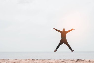 Tropikal kum plaj arka planda atlama mutlu adam. Özgürlük iyi ve yaz tatil konsepti hissediyorum. 