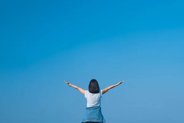 Kopierraum der Frau heben die Hände auf leeren blauen Himmel abstrakten Hintergrund. Freiheit zum Wohlfühlen und Sommerferienkonzept. — Stockfoto