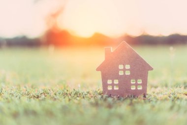 Ev ve yaşam kavramının alanı kopyalayın. Küçük model ev güneş ışığı arka plan ile yeşil çimenlerin üzerinde.