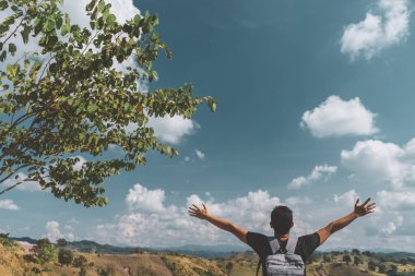 Backpacker adam altında el kadar mavi gökyüzü ve bulutlar beyaz arka plan ile dağın zirvesinde yükseltmek.