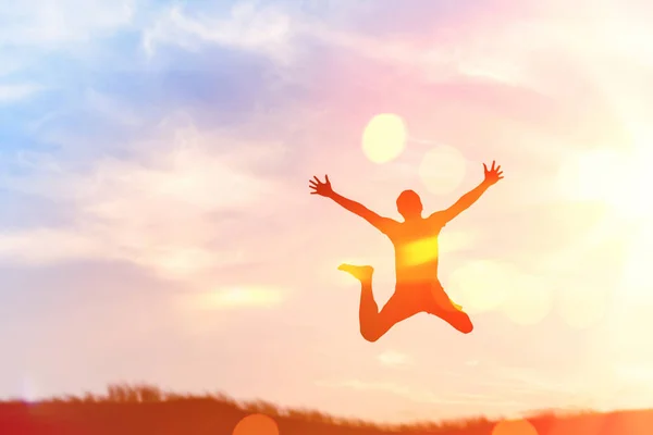 Szczęśliwy człowiek, skoki na szczyt góry zachód słońca niebo streszczenie tło. — Zdjęcie stockowe