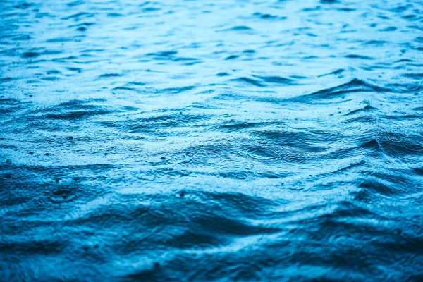 Fechar a superfície da onda mar azul com gotas de chuva fundo abstrato . — Fotografia de Stock
