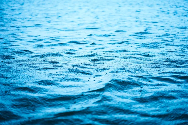 Fechar a superfície da onda mar azul com gotas de chuva fundo abstrato . — Fotografia de Stock