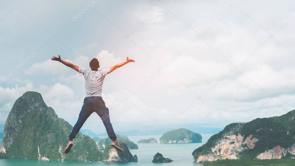 Happy man jumping on top of mountain with view beach island and blue sky white cloud abstract background. 