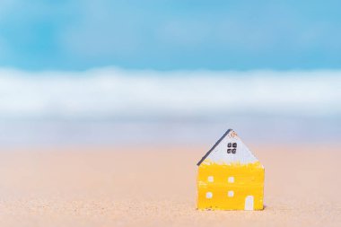 Mavi gökyüzü arka plan ile kum plajında küçük ev modeli.