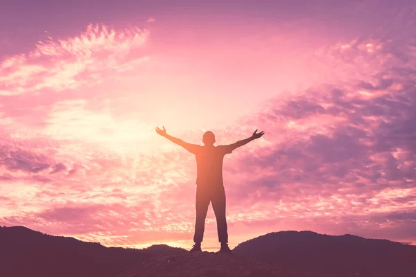 Backpacker homem levantar a mão no topo da montanha com céu por do sol e nuvens abstrato fundo . — Fotografia de Stock