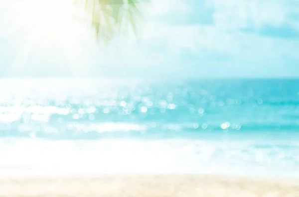 Sfocatura bella natura foglia di palma verde sulla spiaggia tropicale con bokeh sole onda di luce sfondo astratto . — Foto Stock