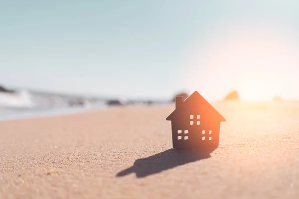Μικρό μοντέλο σπίτι στο ηλιοβασίλεμα παραλία άμμο φόντο υφή. — Φωτογραφία Αρχείου
