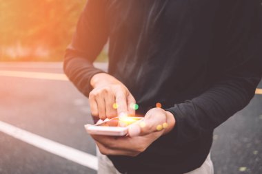 Adam el yakından tutun park açık sokak arka plan üzerinde akıllı telefon kullanma.