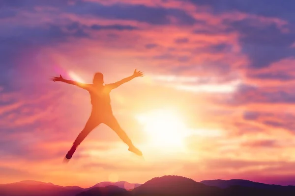 Glücklicher Mann springt auf dem Gipfel des Berges mit Sonnenuntergang Himmel abstrakten Hintergrund. — Stockfoto