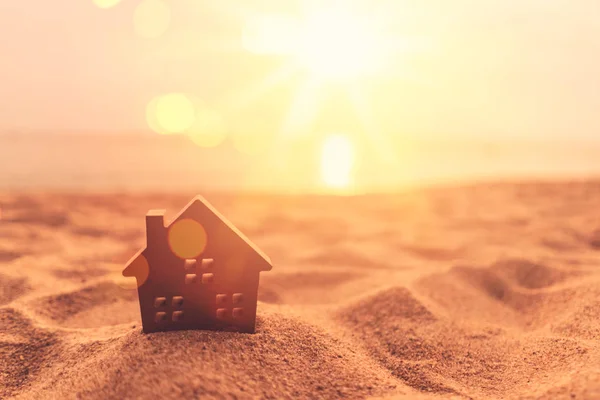 Modelo pequeno casa no pôr do sol praia areia textura fundo . — Fotografia de Stock
