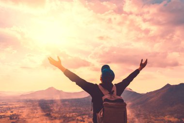 Backpacker adam altında el kadar günbatımı gökyüzü ile dağın zirvesinde yükseltmek ve arka plan bulutlar soyut.