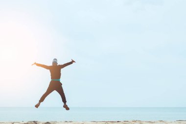 Tropikal kum plaj arka planda atlama mutlu adam. Özgürlük iyi ve yaz tatil konsepti hissediyorum.