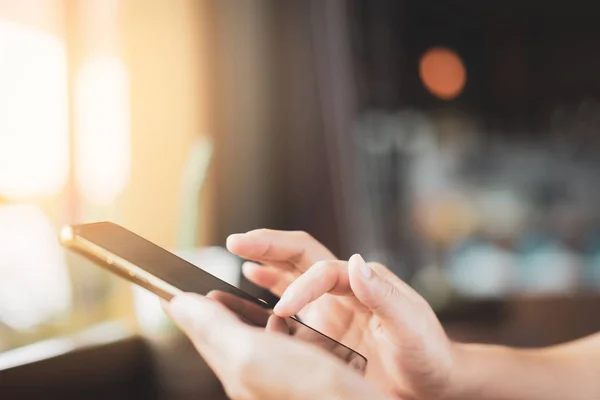 Kvinna hand med hjälp av smart telefon på gamla trä tabell textur bakgrund på Coffee Shop. — Stockfoto