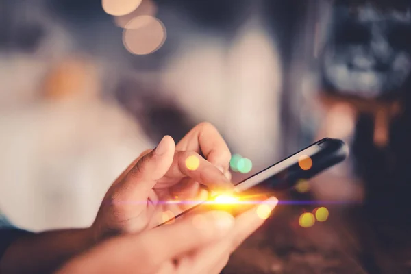 Kvinna hand med hjälp av smart telefon på gamla trä tabell textur bakgrund på Coffee Shop. — Stockfoto