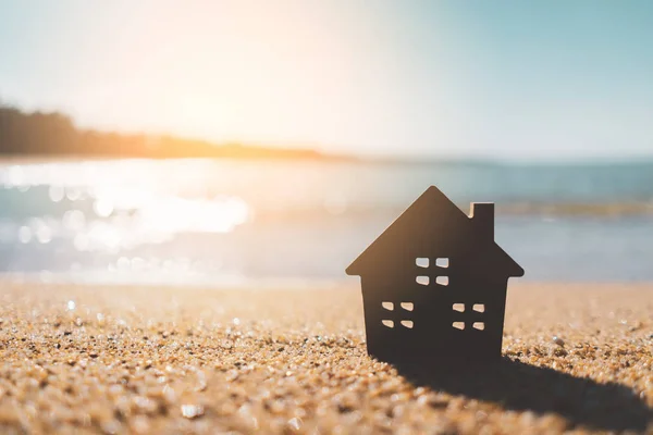 Modelo pequeno casa no pôr do sol praia areia textura fundo . — Fotografia de Stock