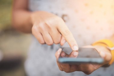 Kadın el yakından tutun park açık sokak arka plan üzerinde akıllı telefon kullanma.