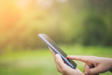 Kadın eli açık doğa Park günbatımı gökyüzü arka plan ile akıllı telefon kullanma.