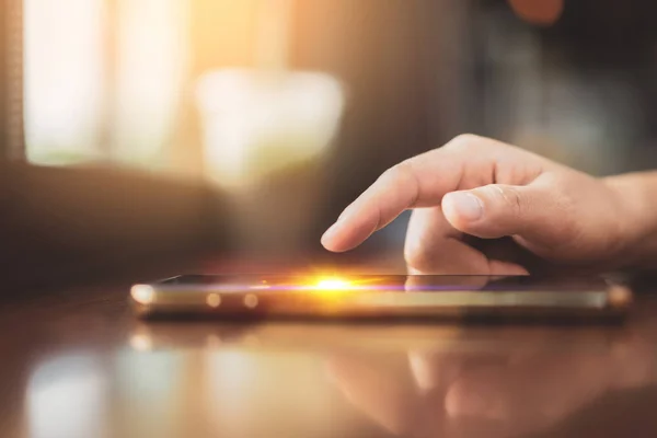 Kvinna hand med hjälp av smart telefon på gamla trä tabell textur bakgrund på Coffee Shop. — Stockfoto