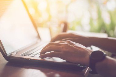 Kahve dükkanında ahşap masada klavye dizüstü bilgisayar kullanarak Adam el.