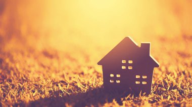 Ev ve yaşam kavramının alanı kopyalayın. Küçük model ev güneş ışığı arka plan ile yeşil çimenlerin üzerinde.