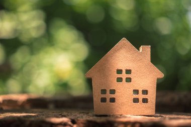 Ahşap masadaki küçük ev modeli, doğa yeşil bokeh soyut arka plan. Aile hayatı ve iş yeri konsepti. 