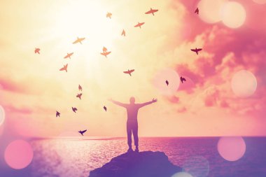 Sahilde ve adada insanın günbatımında gökyüzünde elini kaldırmasını kopyala.