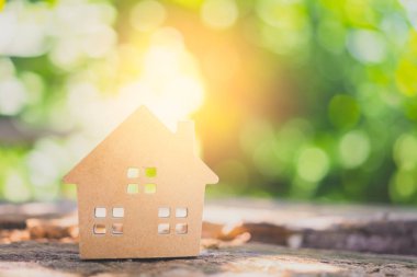 Ahşap masadaki küçük ev modeli, doğa yeşil bokeh soyut arka plan. Aile hayatı ve iş yeri konsepti.