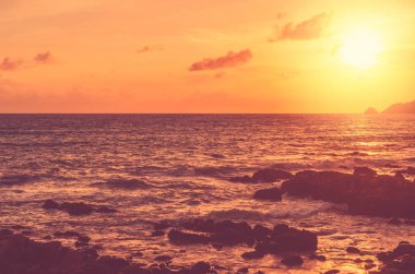 Gün batımı sahili arka planında kayanın üzerine dalga sıçraması. Açık hava yaz tatili ve iş seyahati macera konseptini kopyala.