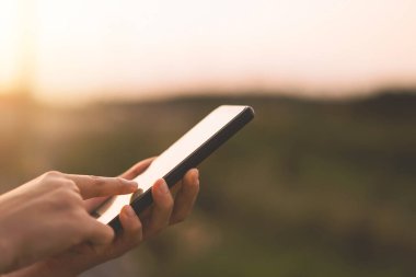 Açık hava parkının arka planında akıllı telefon kullanarak kadının elini tut. Teknoloji ve seyahat tatil konseptinin kopyalama alanı. Klasik ton filtre efekti renk biçimi.