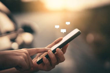 Sokakta uçan sohbet simgesiyle akıllı telefon kullanarak kadın elini kapat. Teknoloji ve seyahat tatil konseptinin kopyalama alanı. Klasik ton filtre efekti rengi.