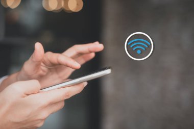 Wi-Fi ikonu soyut arka planı olan akıllı telefon kullanan bir kadın kahve dükkanının renkli bokeh ışığı. Teknoloji işi ve modern yaşam tarzı konsepti. Klasik ton filtre efekti rengi.