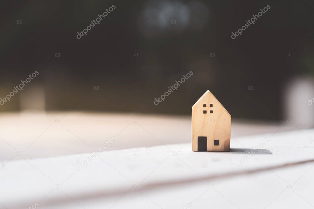 Small home model on wooden table with nature green bokeh abstract background. Family life and business real estate concept. Vintage tone filter effect color style.