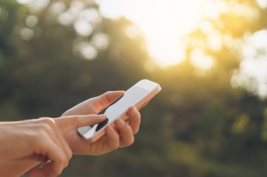 Açık doğa parkında akıllı telefon kullanan bir kadın. Gökyüzü soyut arkaplanı var. Uzay teknolojisi ve seyahat doğası tatil konseptini kopyalayın. Klasik ton filtre efekti renk biçimi.