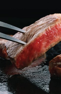 Wagyu bifteği parçalarıyla çatal oyma tahtaya yakın çekim.