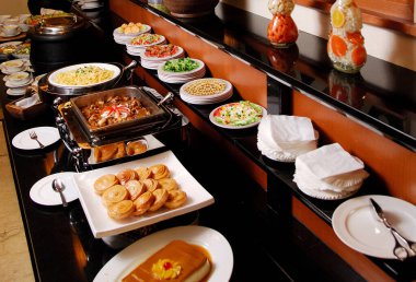 Lezzetli yemekler ve taze sebze salatası ile açık büfe masası.