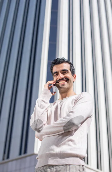 young smiling executive man next to offices talking on the phone