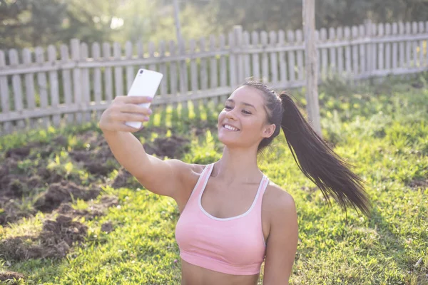 Young beautiful woman runner taking a selfie after finishing training