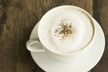 ahşap zemin üzerinde beyaz fincan cappuccino kahve