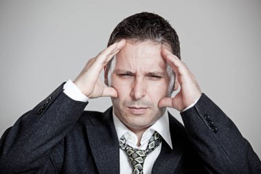 Gri arka plan üzerinde stres baş ağrısı ile yorgun işadamı