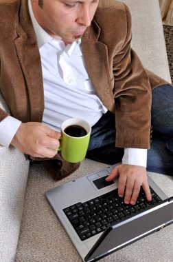 İş yeri kavramı. Huzur içinde ciddi ofis çalışanı bir video izlerken konsantre hizmet istimal onun laptop ve dikkatli bir şekilde çay içme internette