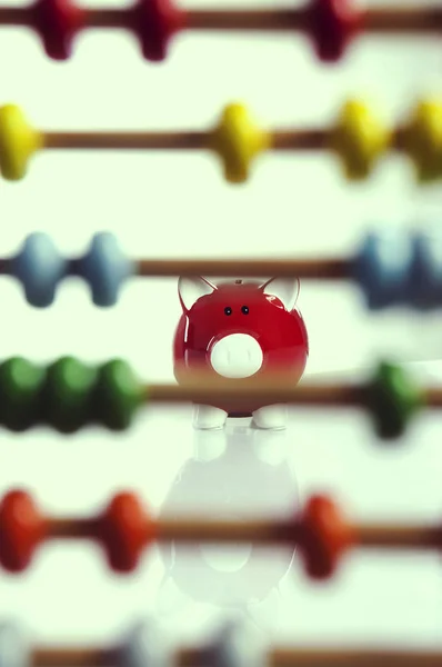 Kırmızı banka, tasarruf hesaplarını gösteren bir abaküsün arkasında oturuyor