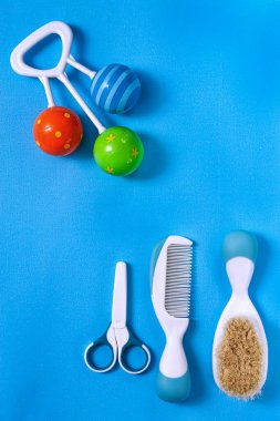 Yeni doğanlar için aksesuarlar, taraklar, makas, mavi arka planda tıngırtılar, üst görünüm