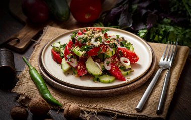  Domates ve salatalıklı sebze salatası, kırmızı soğan, acı biber, ceviz, geleneksel bir Gürcü yemeği, kırsal bir masada.