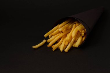 french fries on a black background, in a black package, horizontal clipart