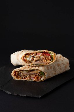 Shawarma, lavaşta yuvarlan, ızgara et, sebzeli, sandviçli, siyah arka planda kesilmiş, dikey, kopyalama spazmı